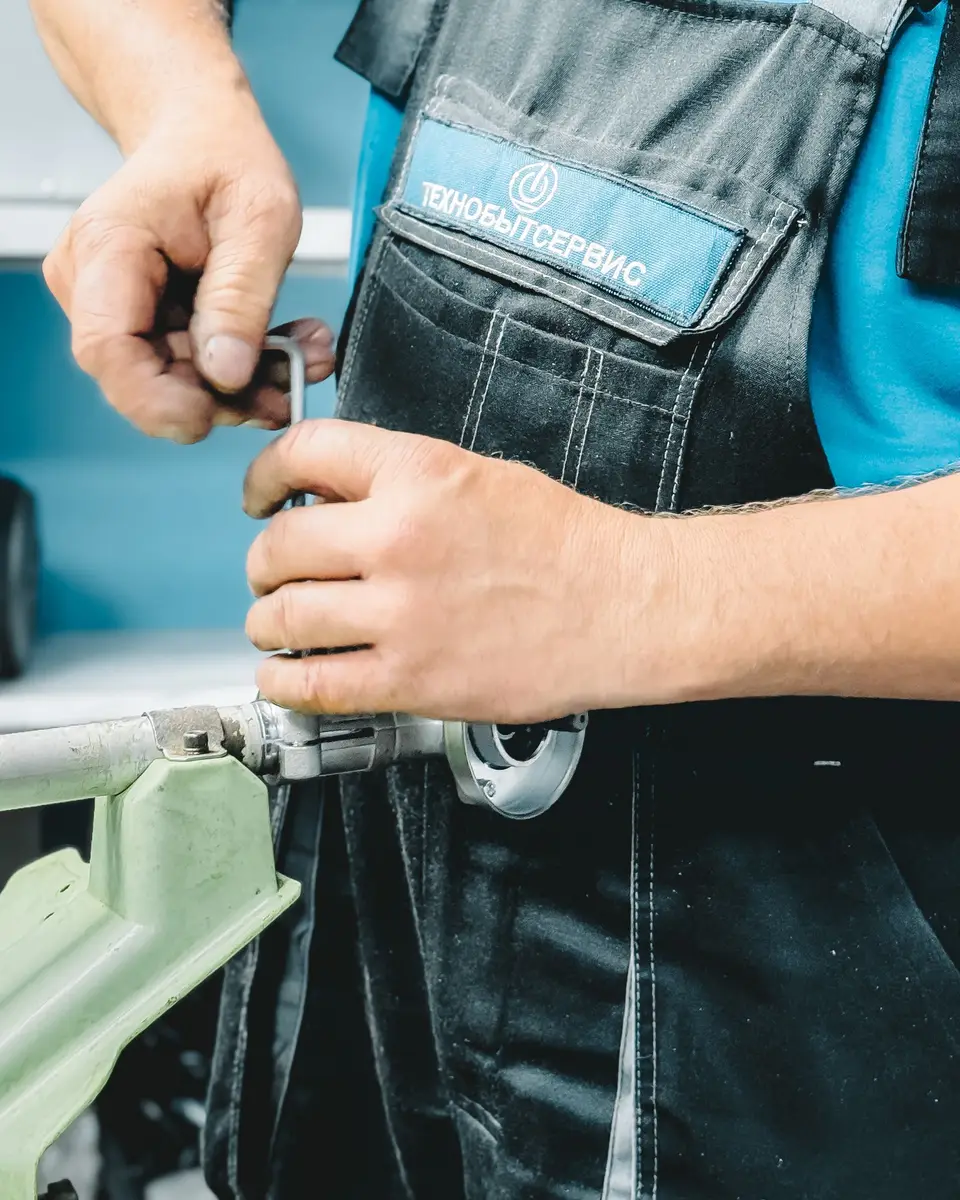 Plumber in work overalls tightening a pipe fitting